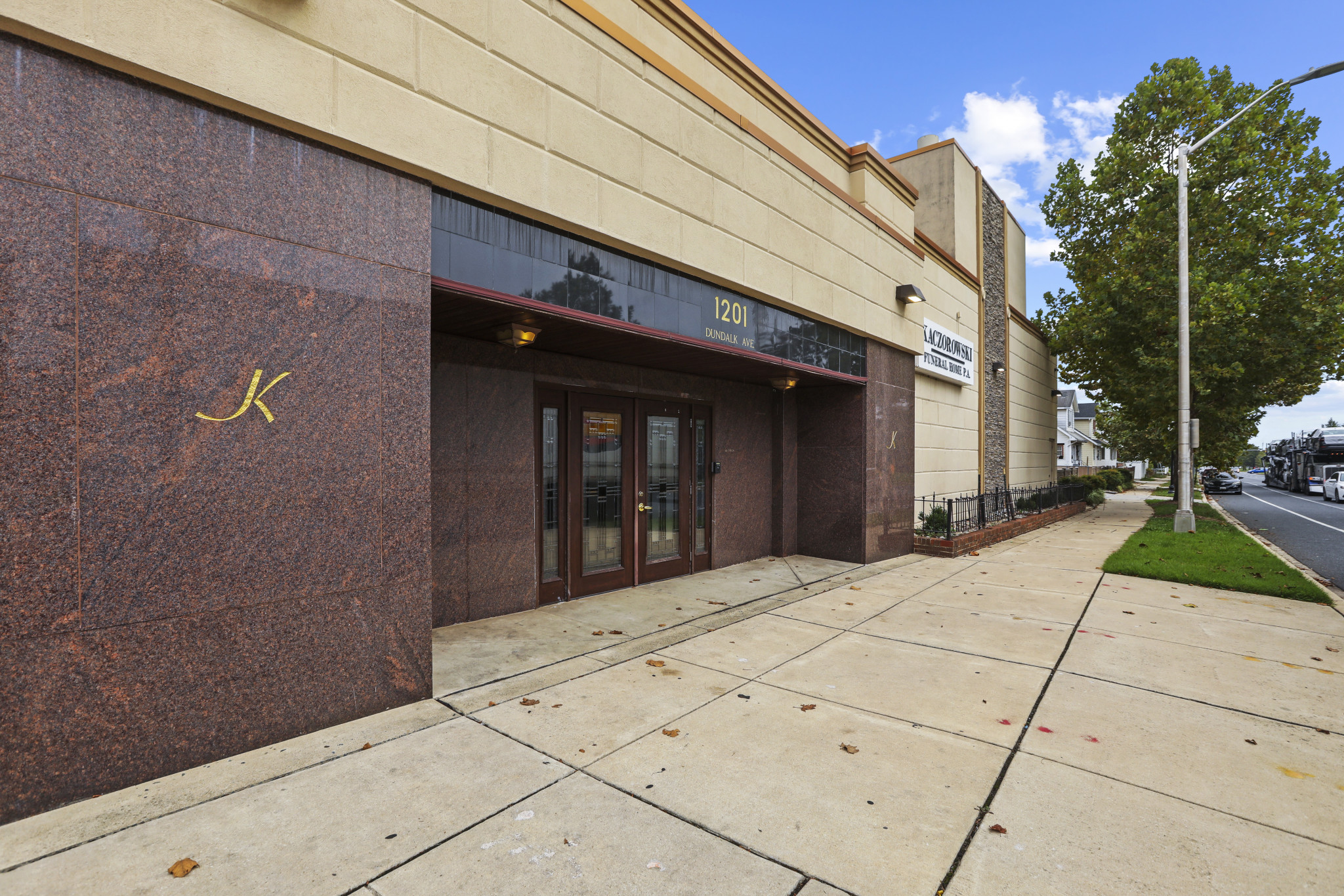Kaczorowski Funeral Home entrance — granite facade with gold K insignia